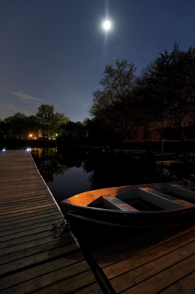 •• Moonlight is reflected off of a boat at the rowing club in Bandemer Park.